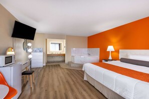 A hotel room with a bed, a desk, a TV, a bathroom, and a window.