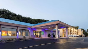 Ein modernes Hotel mit blauem Dach, großen Fenstern und einem überdachten Eingangsbereich.