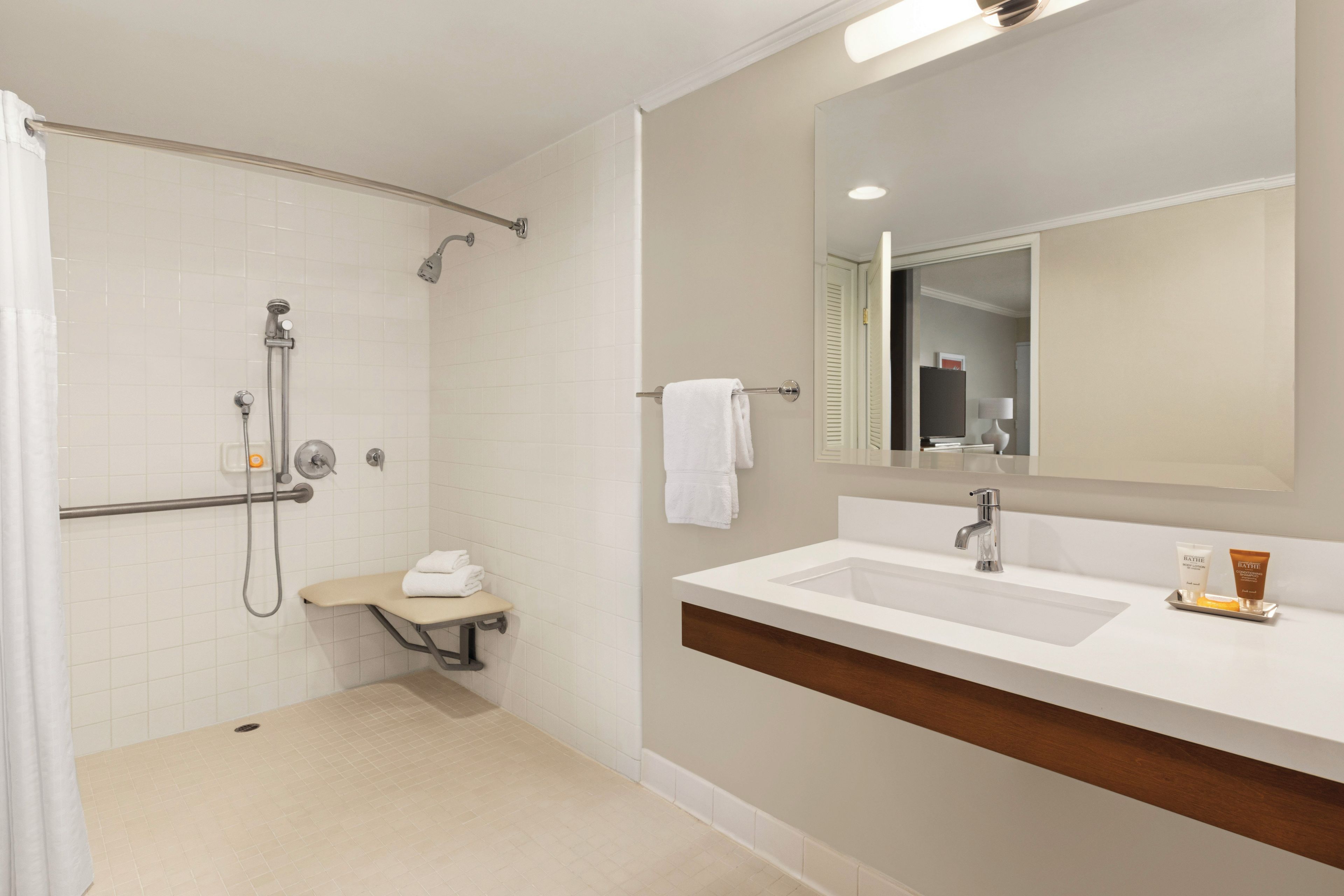 Un baño moderno con ducha a ras de suelo, tocador con espejo y artículos de aseo.