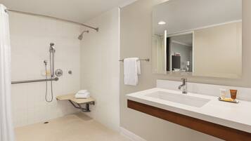 Un baño moderno con ducha a ras de suelo, tocador con espejo y artículos de aseo.