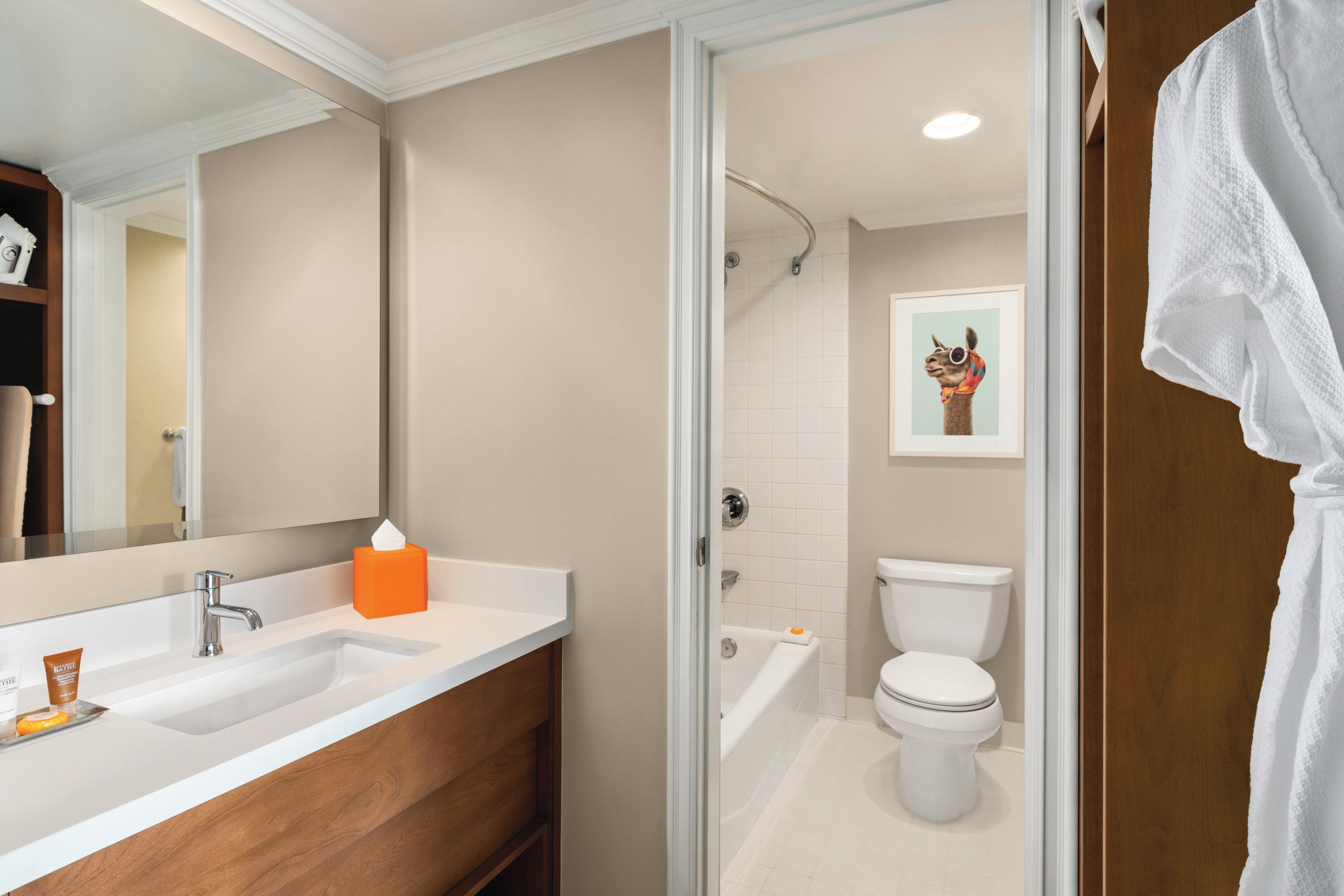 A bathroom with a double sink, a toilet, a shower, and a mirror.