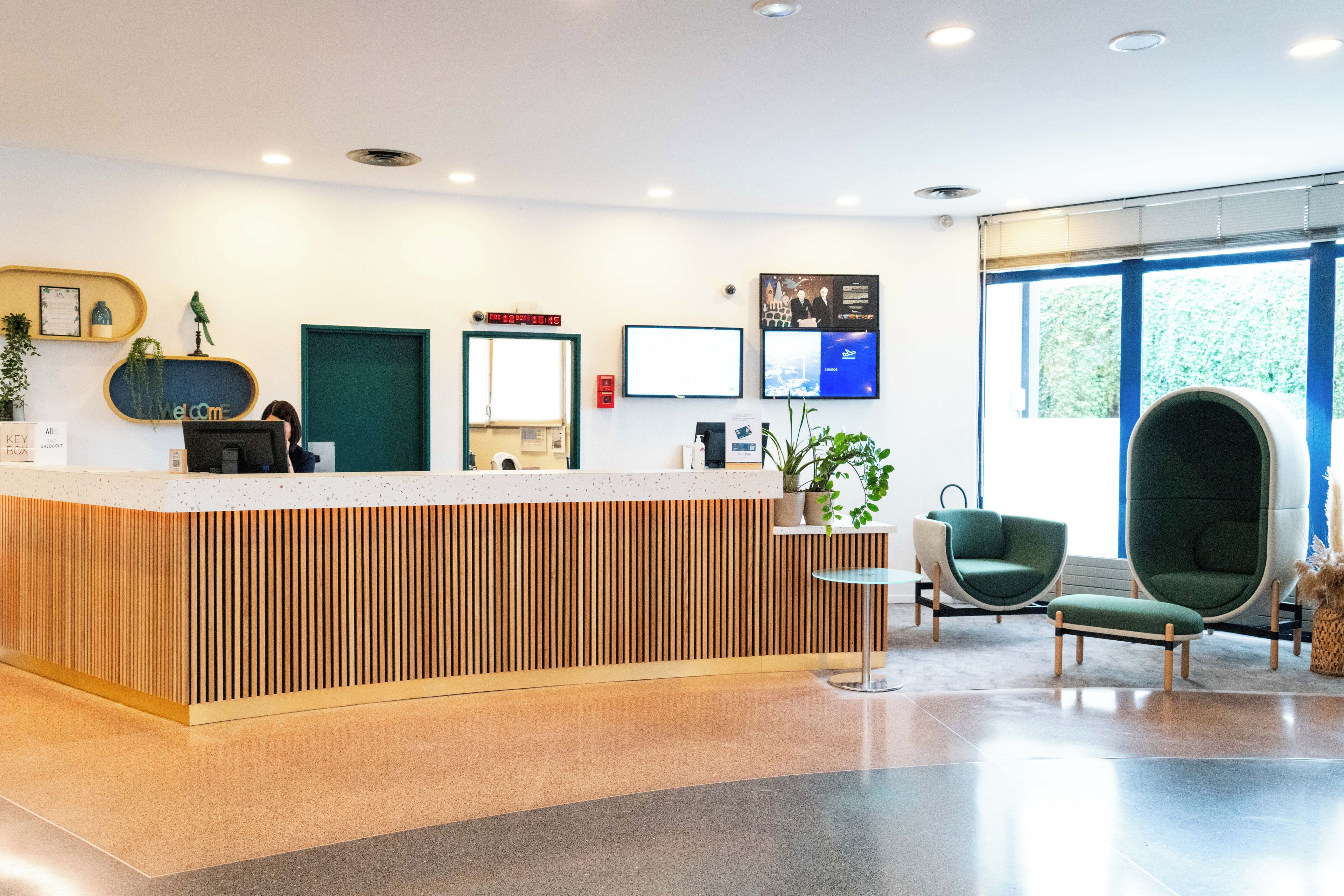 A reception desk with a wooden panel design, a digital clock, and a framed welcome sign.