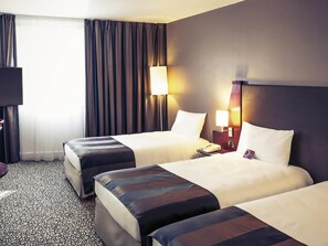 Une chambre dâhĂŽtel avec deux lits, un bureau, un tĂ©lĂ©phone et une lampe.