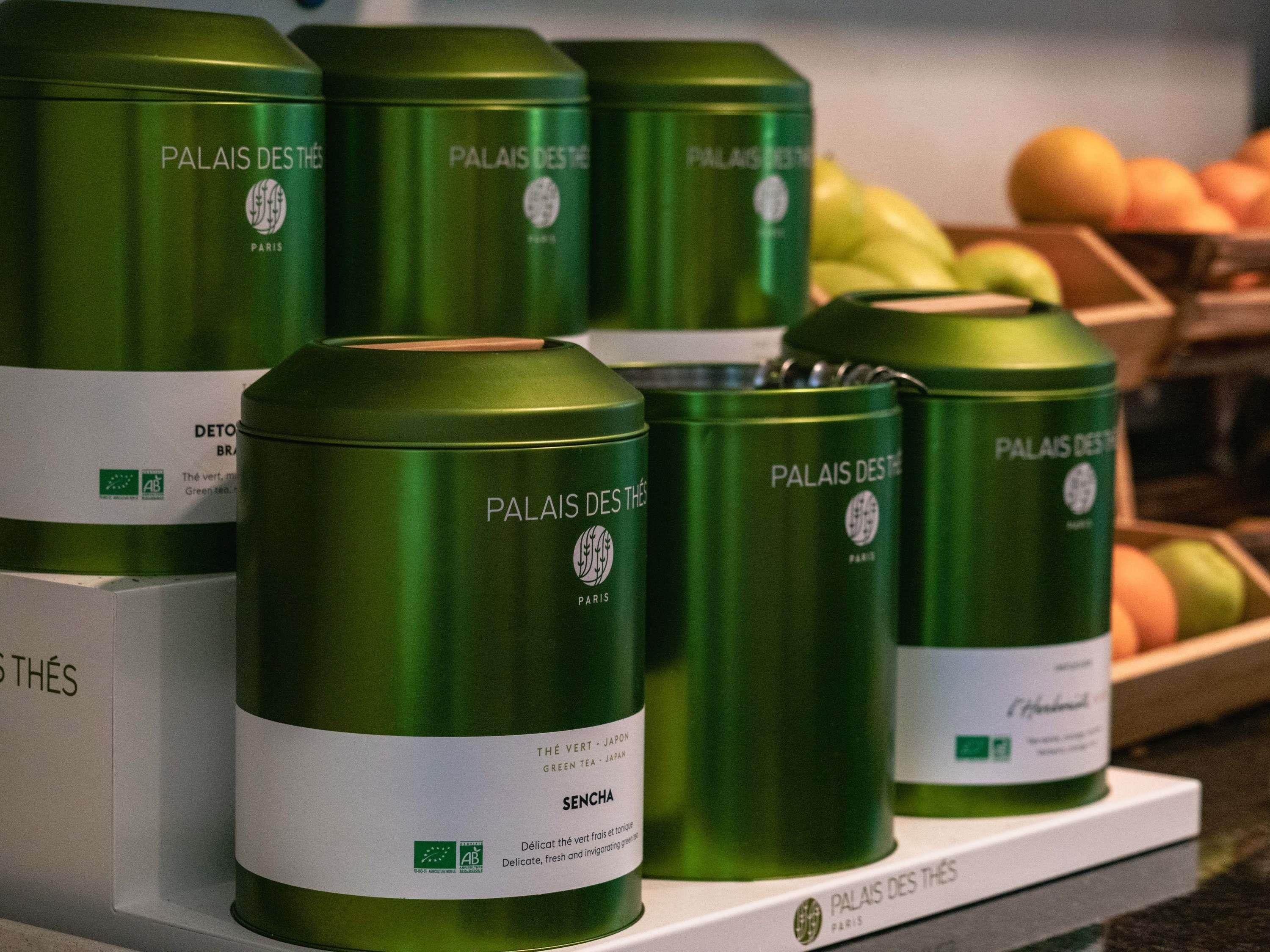 Green cans of 'Palais Des Thés' tea on a shelf.