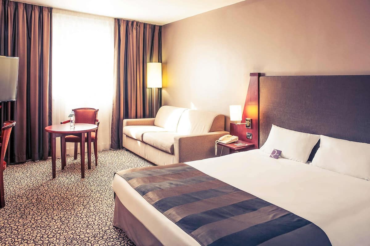Une chambre dâhĂŽtel Ă©quipĂ©e dâun lit, dâun bureau, dâune chaise, dâune lampe et dâun tĂ©lĂ©phone.