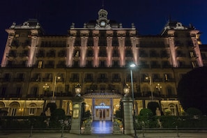 Un hôtel de luxe avec une entrée principale imposante, de grandes colonnes et une tour horloge.