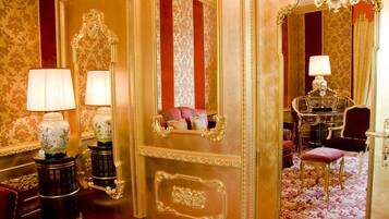 A luxurious room with ornate decor, including a mirror, lamps, and a plush chair.