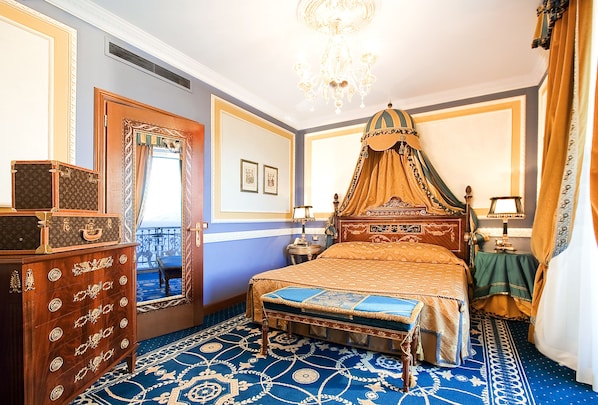 A room with a four-poster bed, a wooden dresser, a chandelier, and a patterned carpet. - Grand Hotel Des Iles Borromees (Stresa)