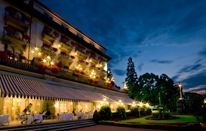 Experience the classic European charm of this hotel, featuring a beautiful balcony with flowers and a welcoming entrance with outdoor seating.