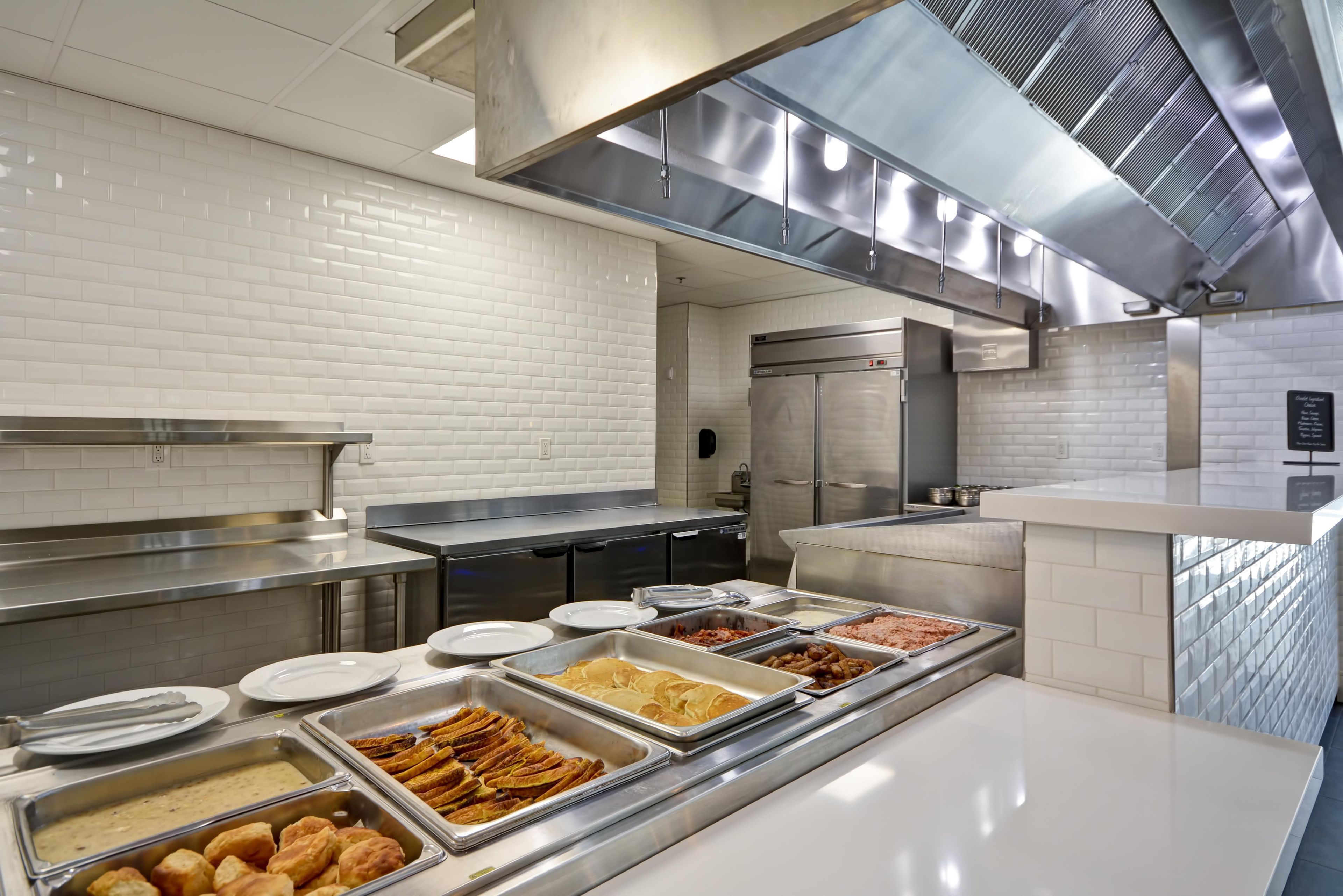A buffet setup with various food items and stainless steel serving equipment.