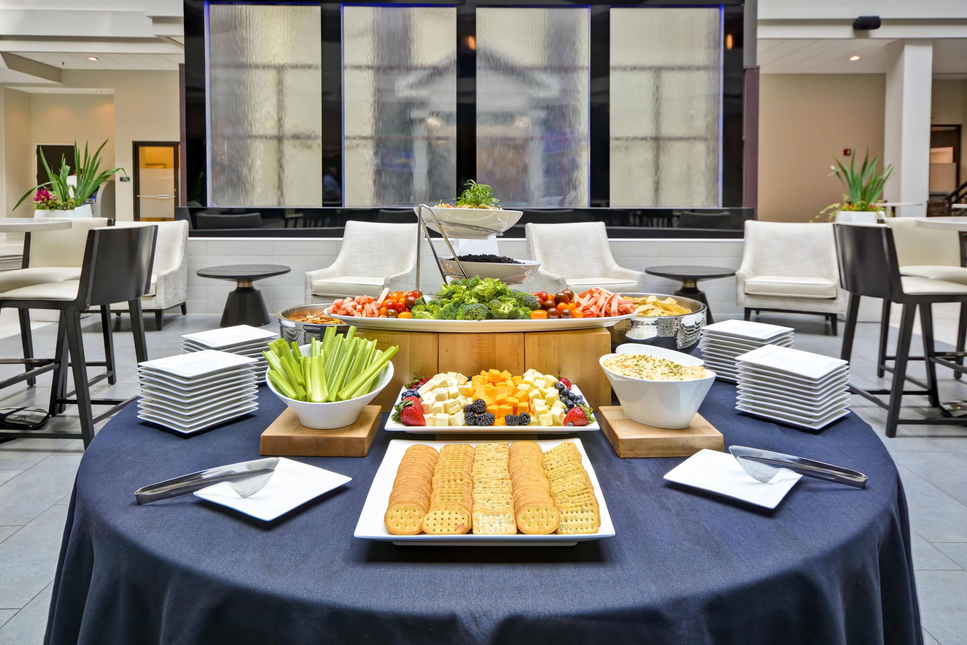 A buffet table with various food items and a large window in the background.