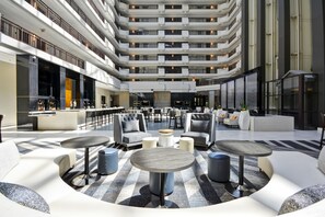 A spacious atrium with multiple seating areas, a bar, and a high ceiling with balconies. - Embassy Suites Hotel Charlotte (Charlotte)