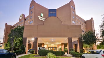 A hotel with a modern design, featuring a prominent entrance and a landscaped garden area.