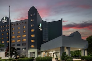 A modern building with multiple floors, a prominent sign for 'Embassy Suites,' and a well-lit entrance area. - Embassy Suites Hotel Charlotte (Charlotte)
