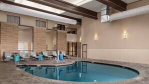 An indoor swimming pool with a tiled floor, lounge chairs, and a second-floor balcony. - DoubleTree by Hilton Lubbock University Area (Lubbock)