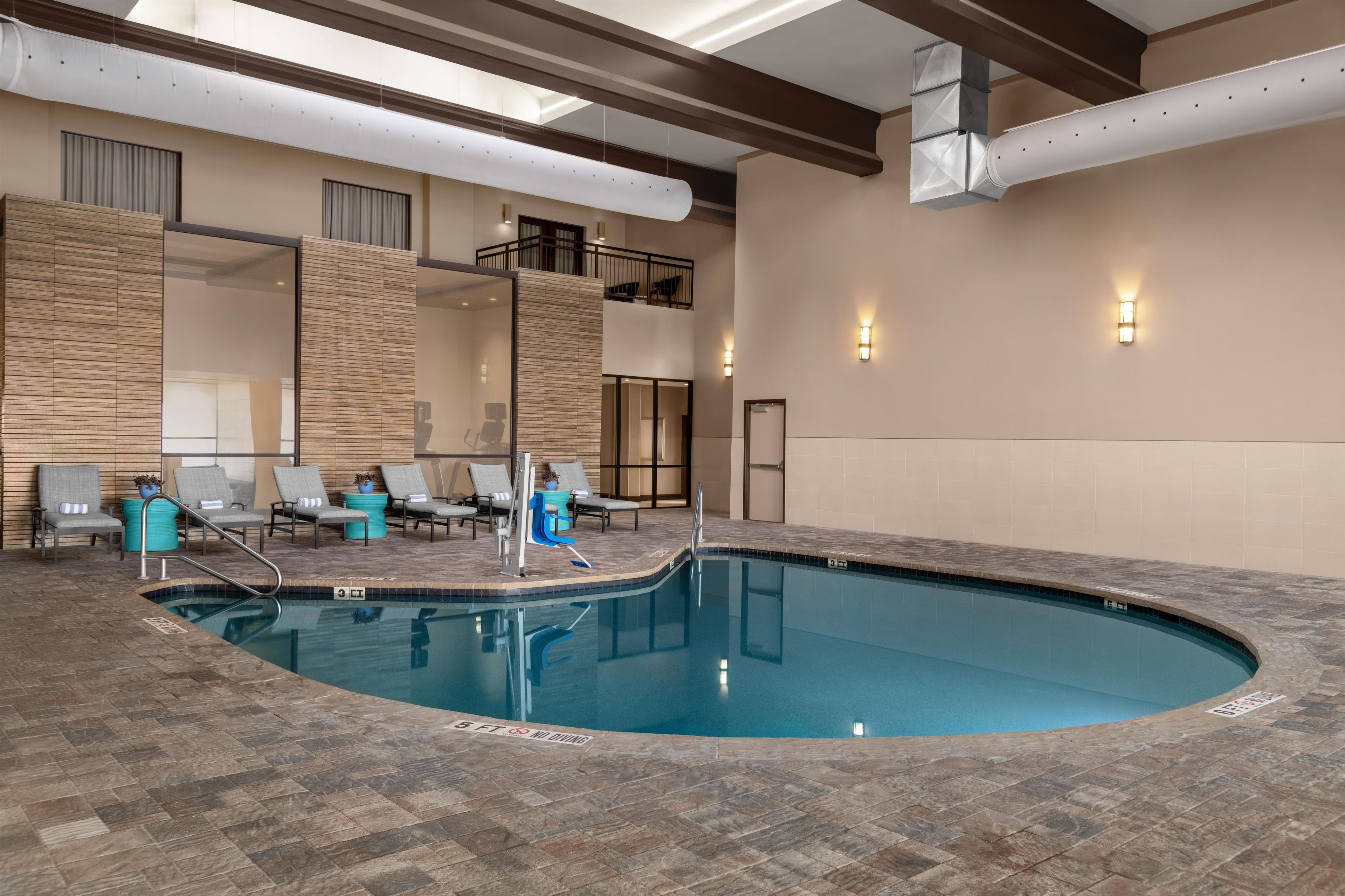 An indoor swimming pool with lounge chairs and a sunbed.