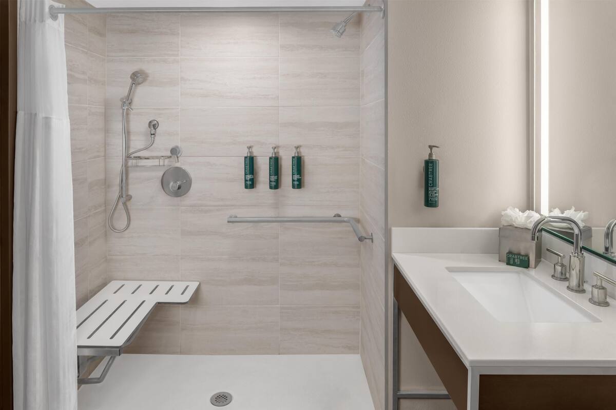 A modern bathroom with a shower, a sink, and a toilet.