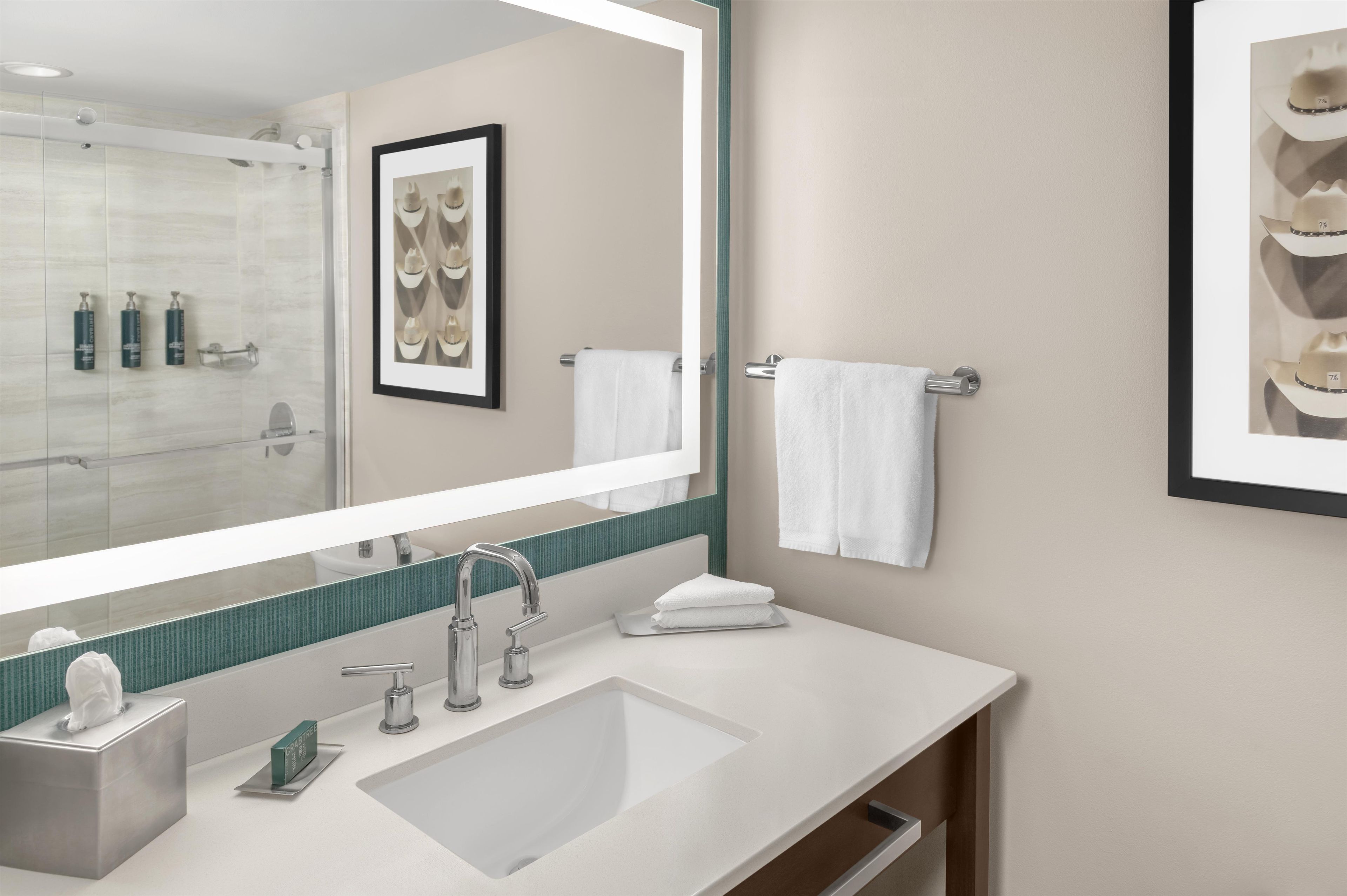 Un baño moderno con un espejo grande, un lavamanos y un cuadro en la pared.