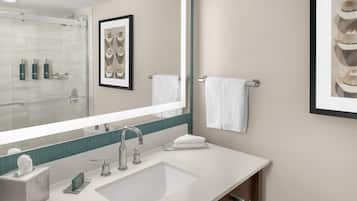 Un baño moderno con un espejo grande, un lavamanos y un cuadro en la pared.