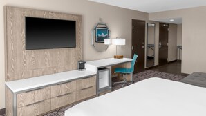 A hotel room with a bed, a desk with a lamp, a TV, a mirror, and a chair. - DoubleTree by Hilton Lubbock University Area (Lubbock)