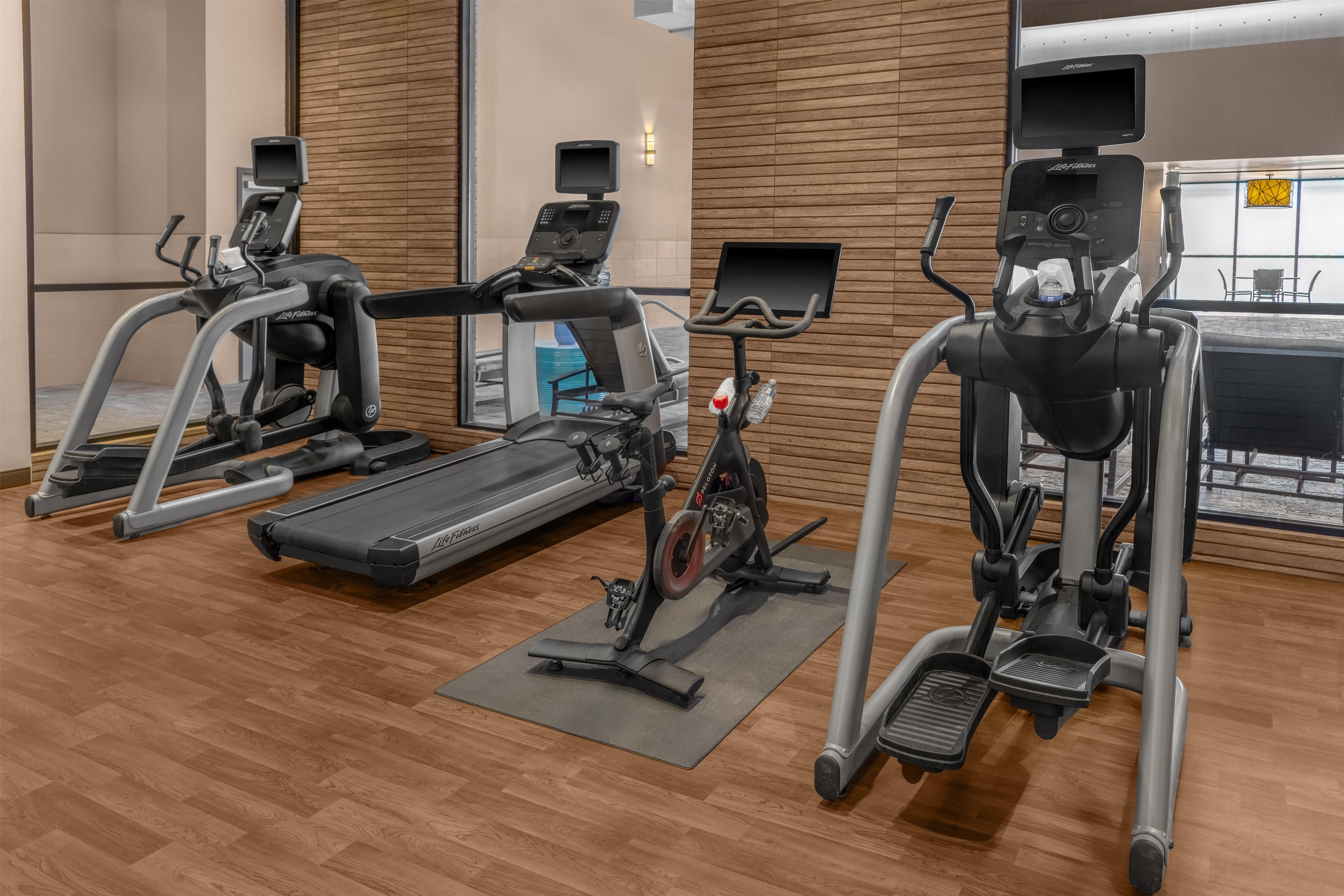 Un gimnasio con cintas de correr, elípticas y una bicicleta estática.
