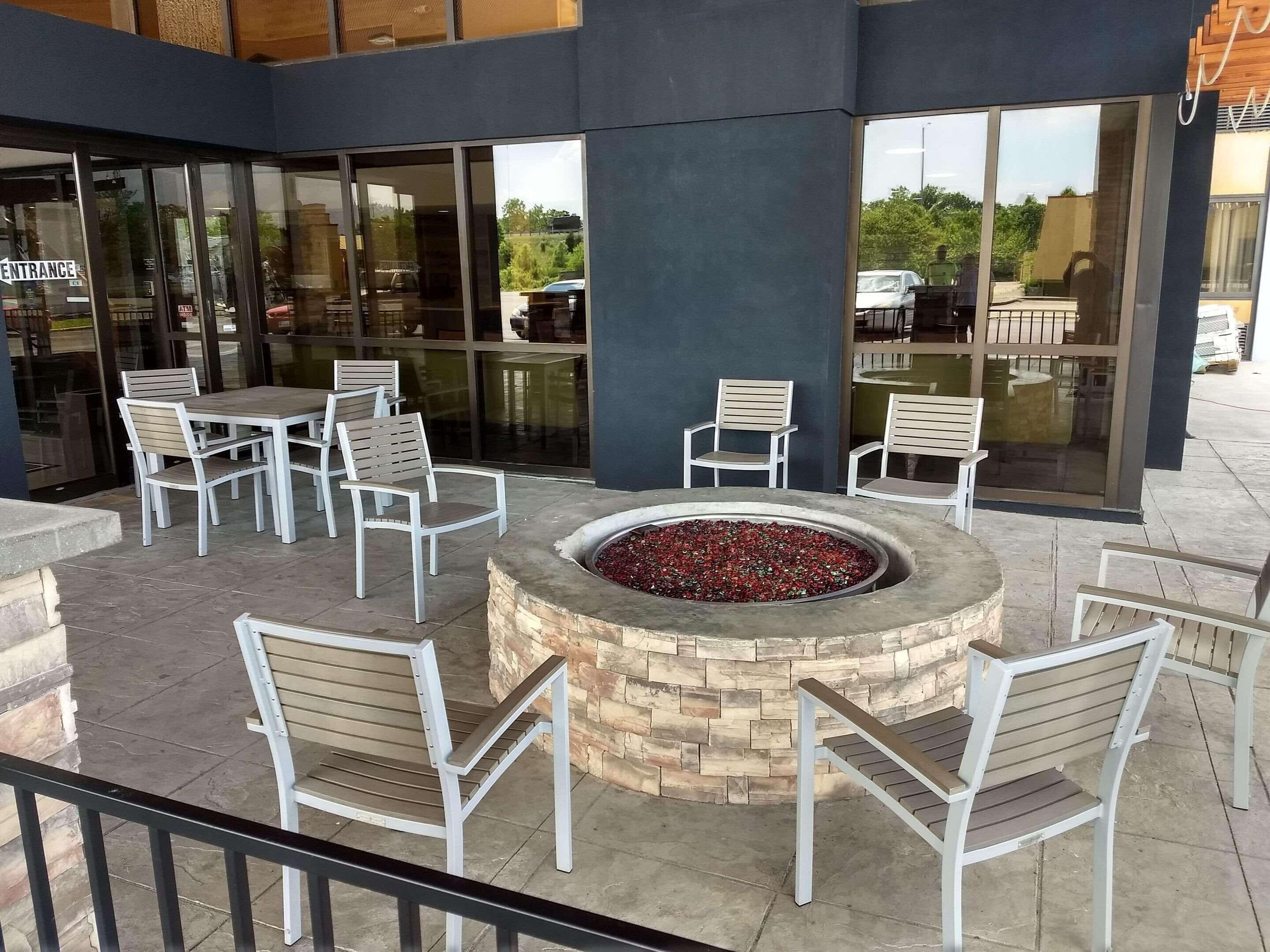 Un espacio al aire libre con sillas blancas y un hogar circular.
