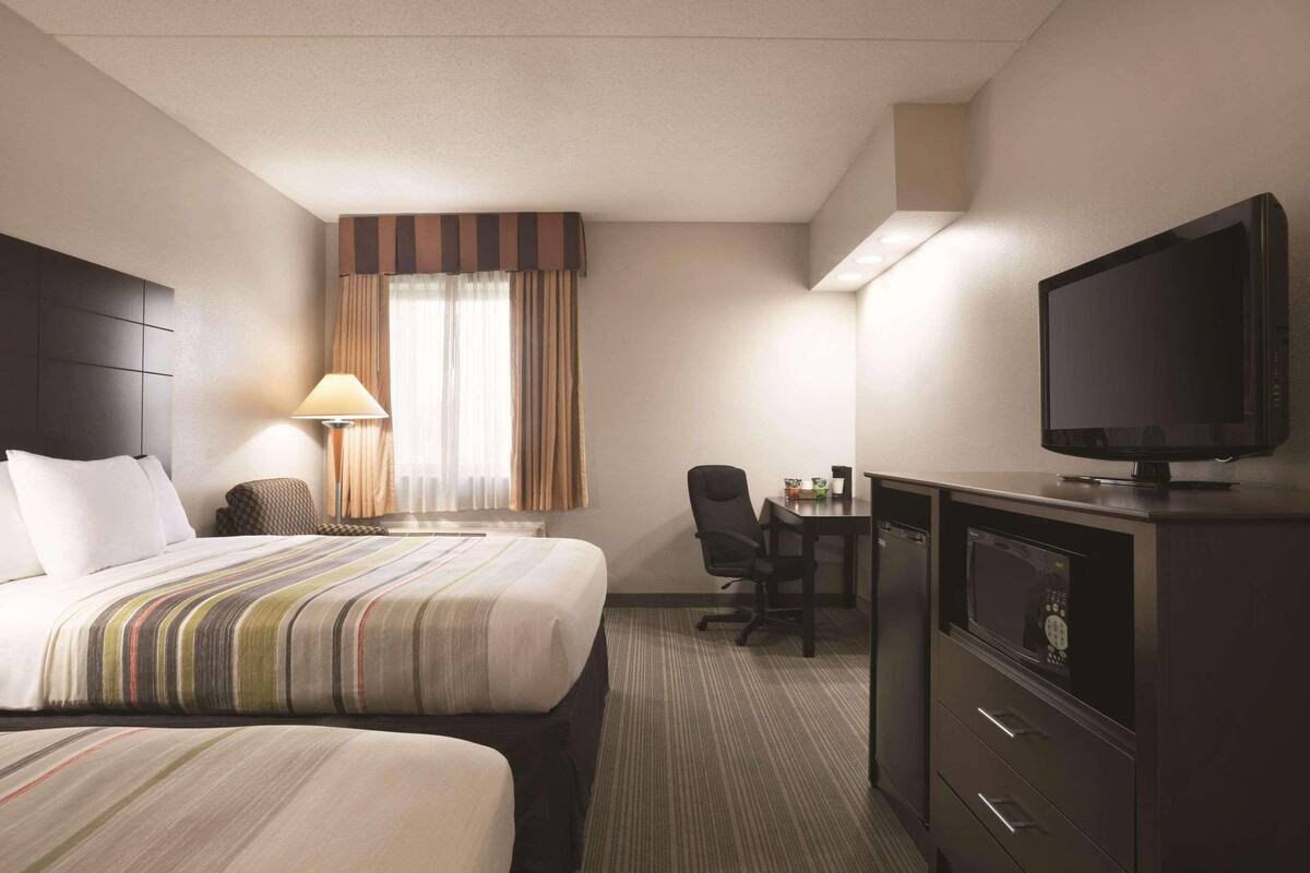 Ein Hotelzimmer mit einem Bett, einem Schreibtisch, einem Stuhl, einem Fernseher und einer Mikrowelle.