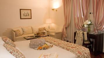 A hotel room with a bed, a sofa, a desk, and a lamp.