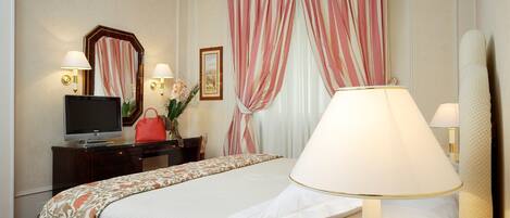 Une chambre d’hôtel avec un lit, des lampes de chevet, une télévision, une commode, un miroir et une fenêtre avec des rideaux.