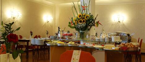 A hotel dining area with a buffet setup, including various food items and a coffee machine.
