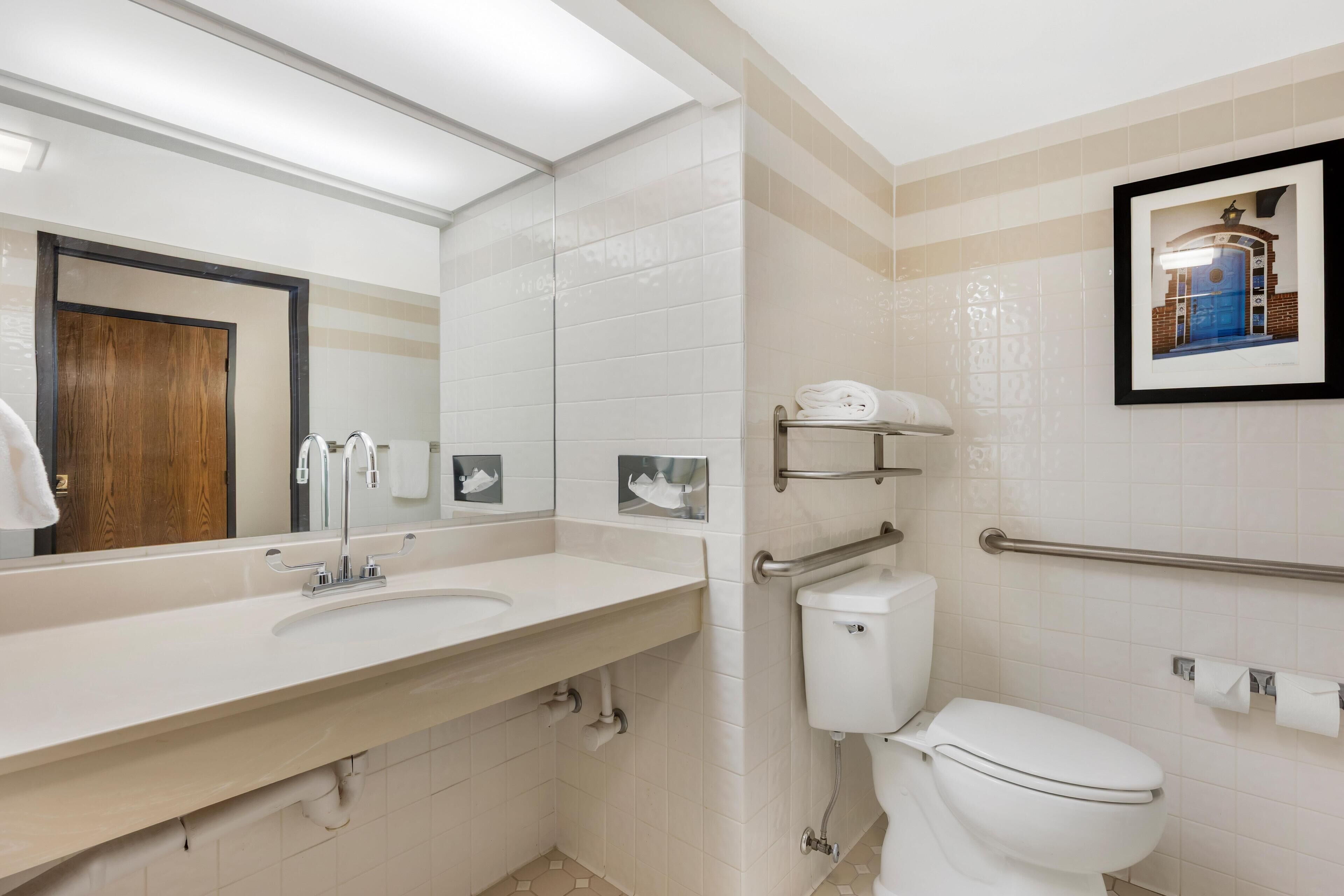 A modern bathroom with a white sink, mirror, and toilet.