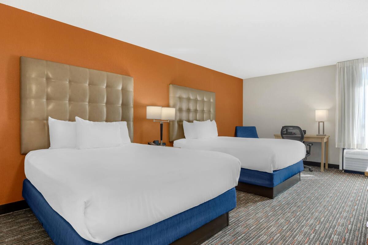 Ein Hotelzimmer mit zwei Betten, einem Schreibtisch und einem Stuhl.