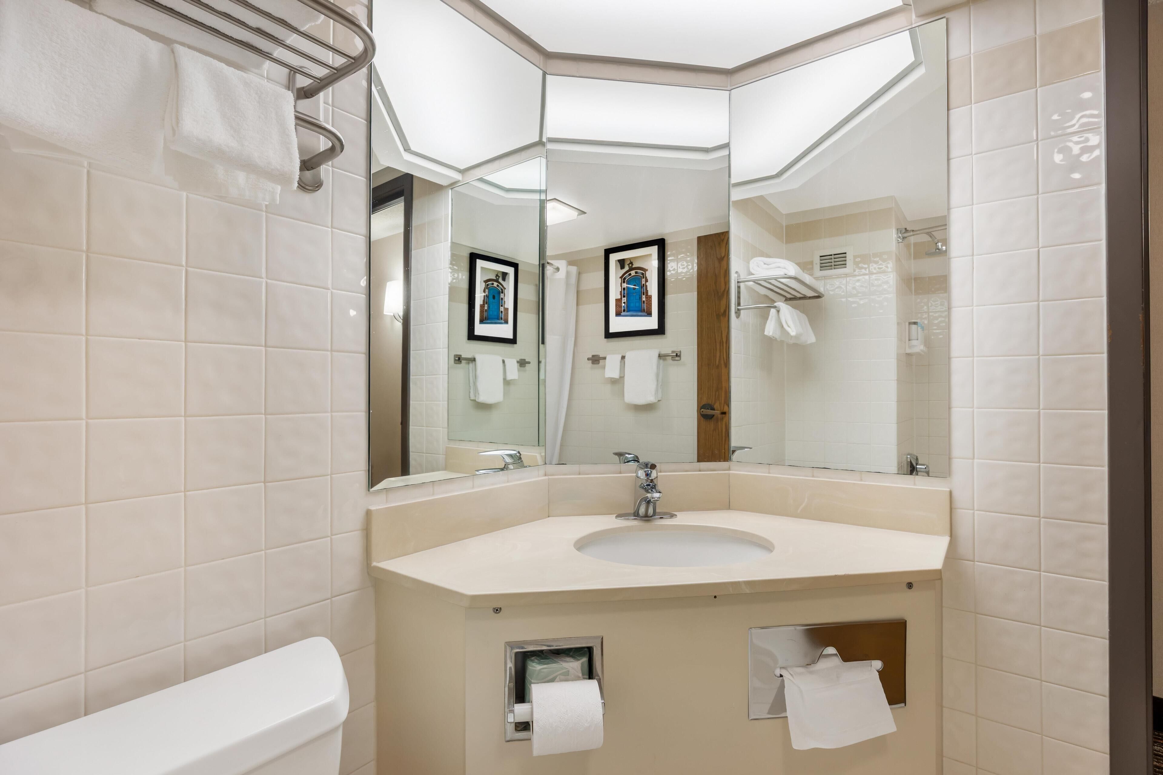 A modern bathroom with a large mirror, a sink, and a toilet.