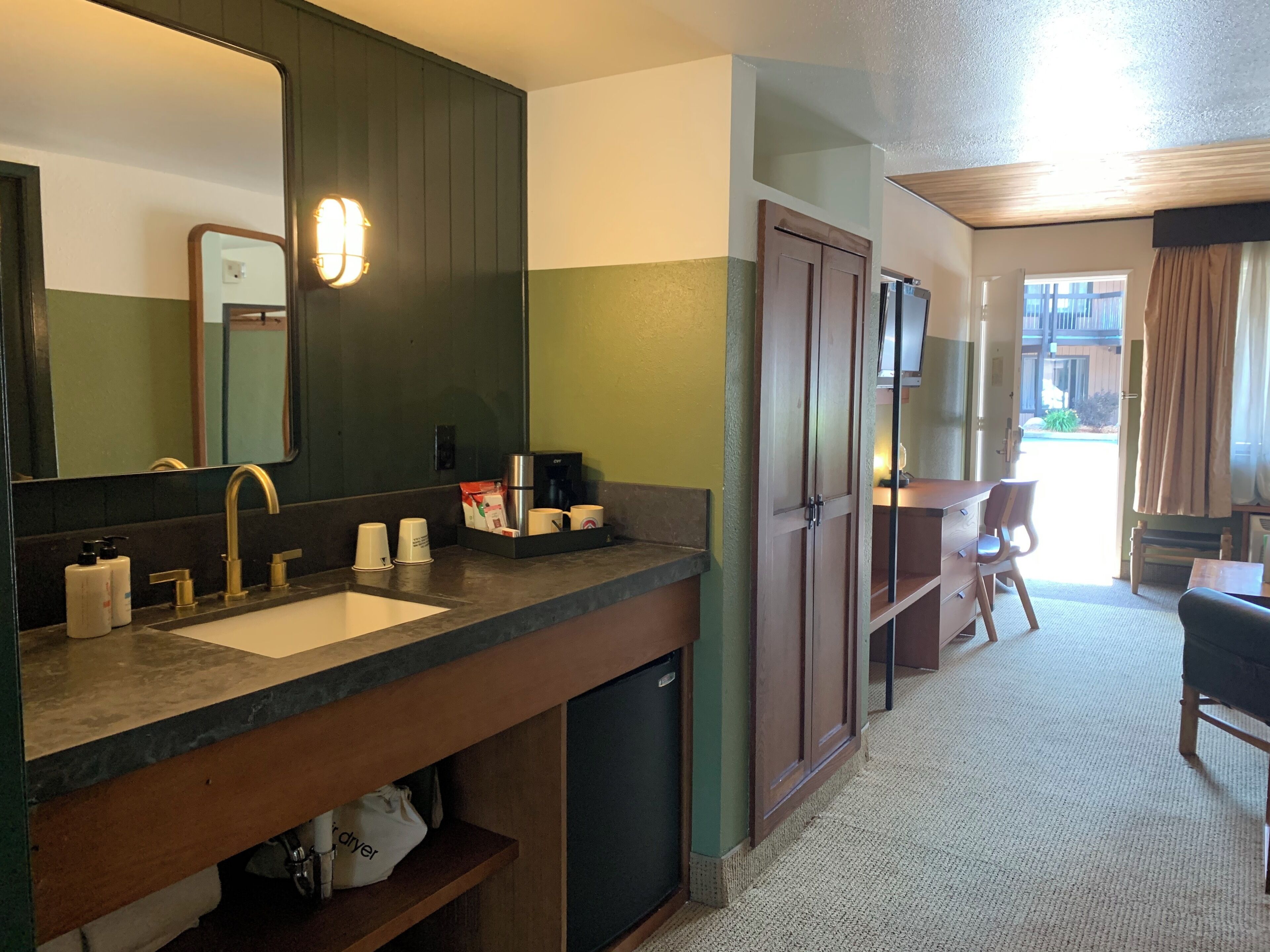 A hotel bathroom with a sink, mirror, and toiletries.