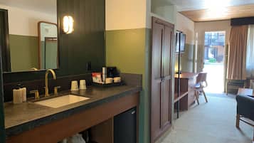 A hotel bathroom with a sink, mirror, and toiletries.