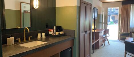 A hotel bathroom with a sink, mirror, and toiletries.