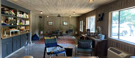 Amplia sala de estar con techo de madera, un sofá, una mesa de centro y una cocina con vistas al exterior.