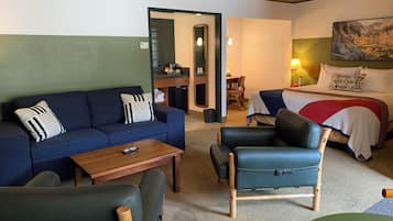 Quarto com sofá, cadeira, cama, mesa pequena e um quadro na parede.