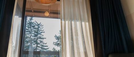 A room with a large window, a wooden table, and a potted plant on the windowsill.