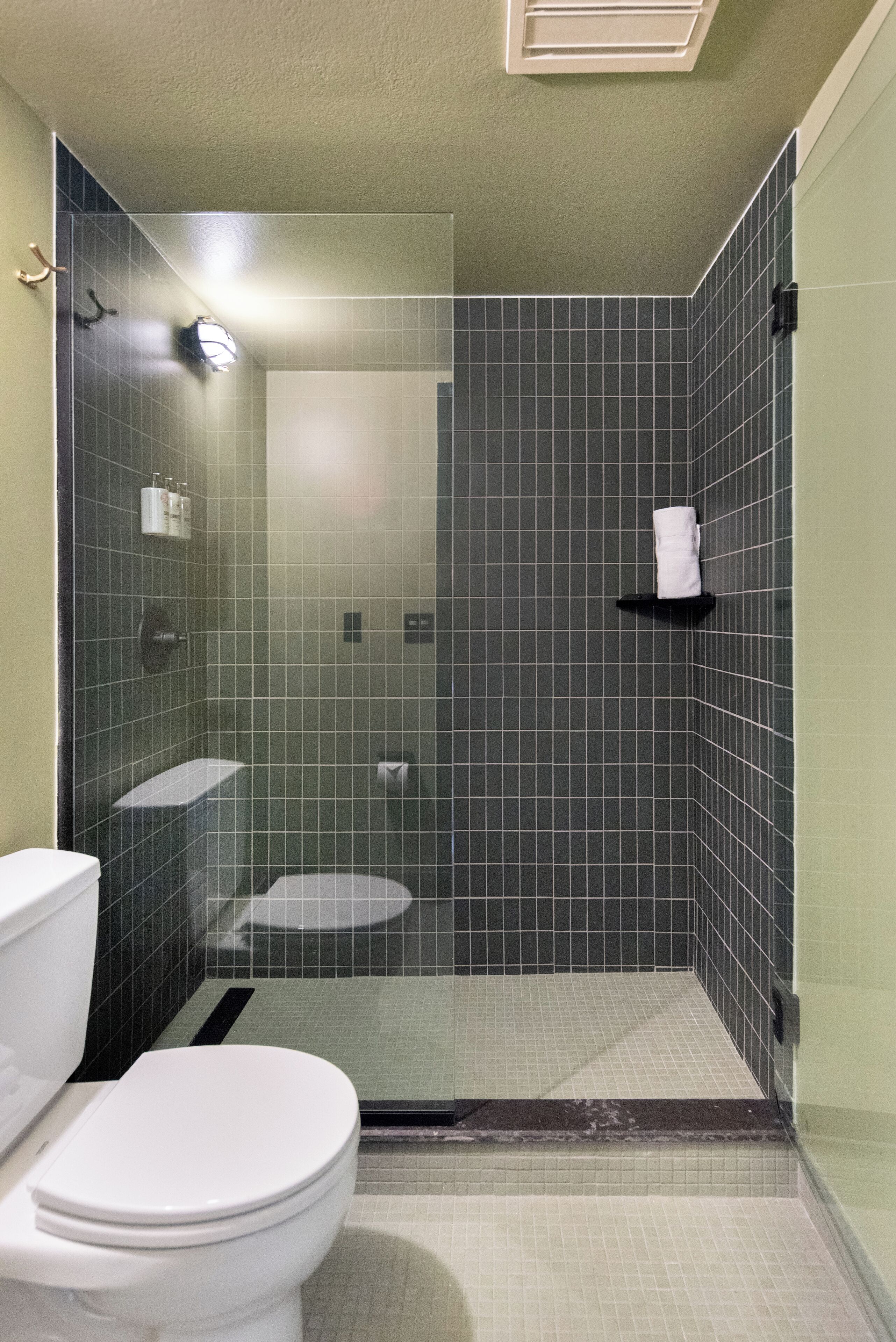 Un baño con inodoro, lavamanos y zona de ducha con puerta de cristal.