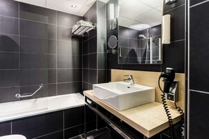 Une salle de bain moderne avec une grande baignoire, un lavabo et un miroir.