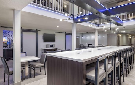 A modern conference room with a long table, chairs, and a television on the wall.