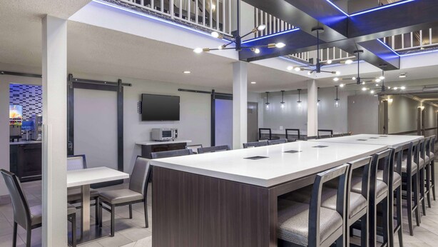 A modern conference room with a long table, chairs, and a television on the wall. - Best Western McCarran Inn (Las Vegas)