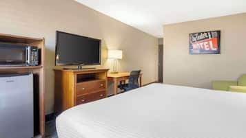 A hotel room with a bed, a desk with a chair, a television, a microwave, and a refrigerator.