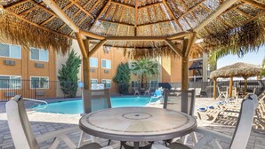 A covered outdoor seating area with a pool in the background. - Best Western McCarran Inn (Las Vegas)