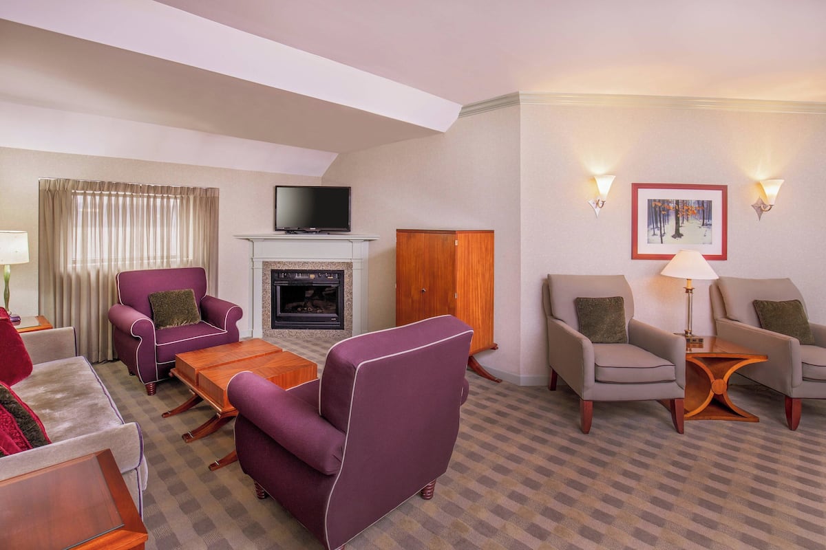 A living room with a fireplace, two armchairs, a sofa, a television, and a lamp.