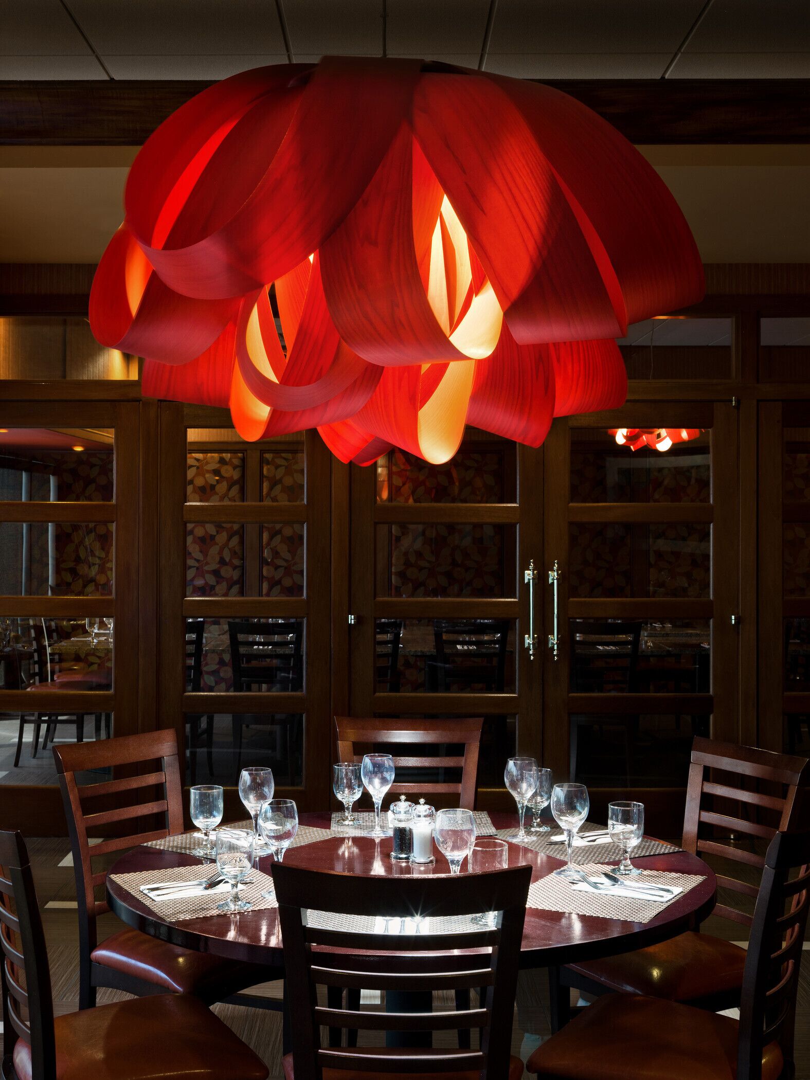 A dining area with a round table set for six, surrounded by wooden chairs.