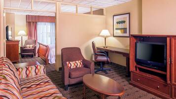 Een hotelkamer met een bank, twee fauteuils, een bureau, een televisie en een lamp.