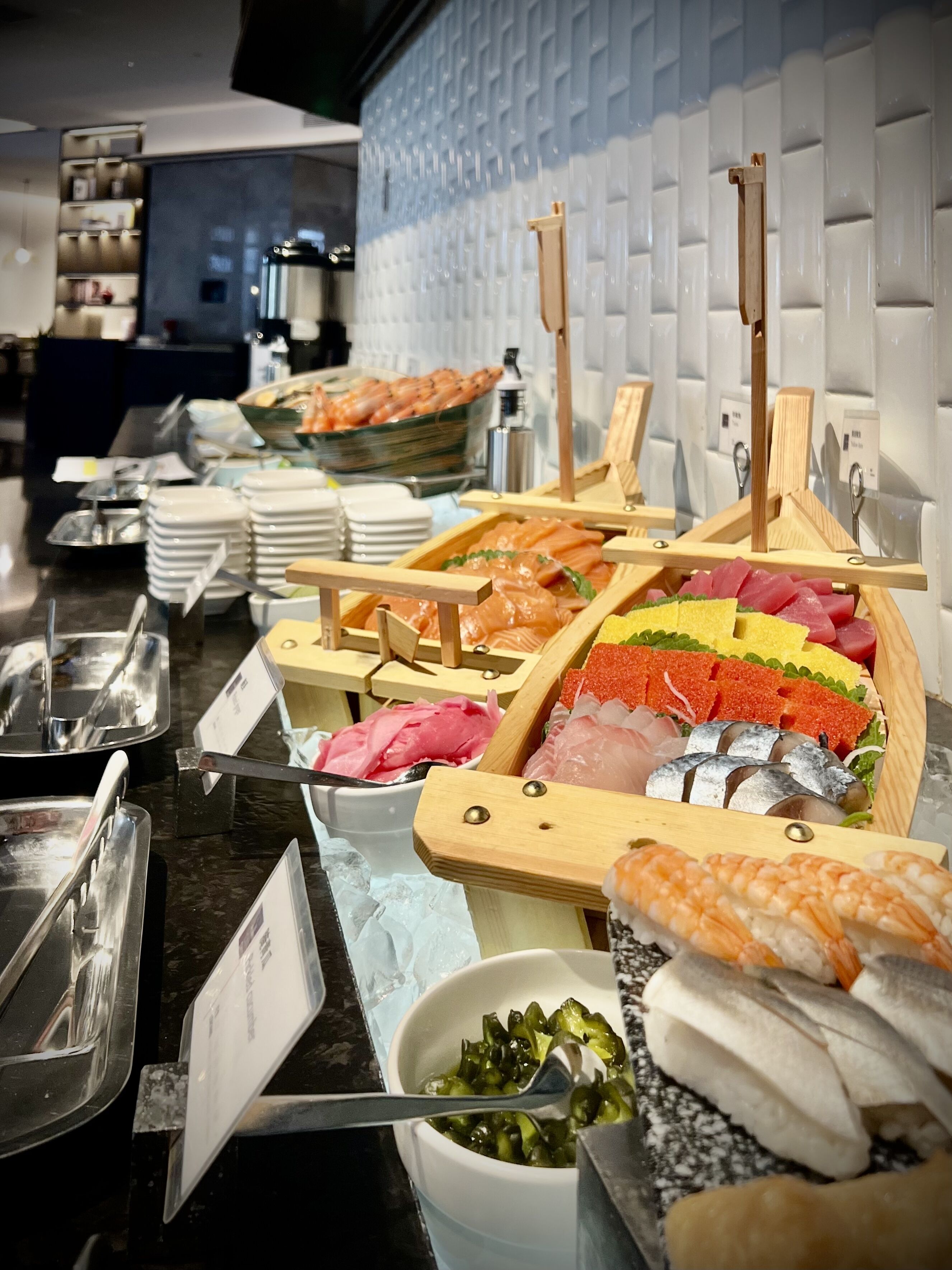 A buffet with various types of seafood displayed on wooden stands.