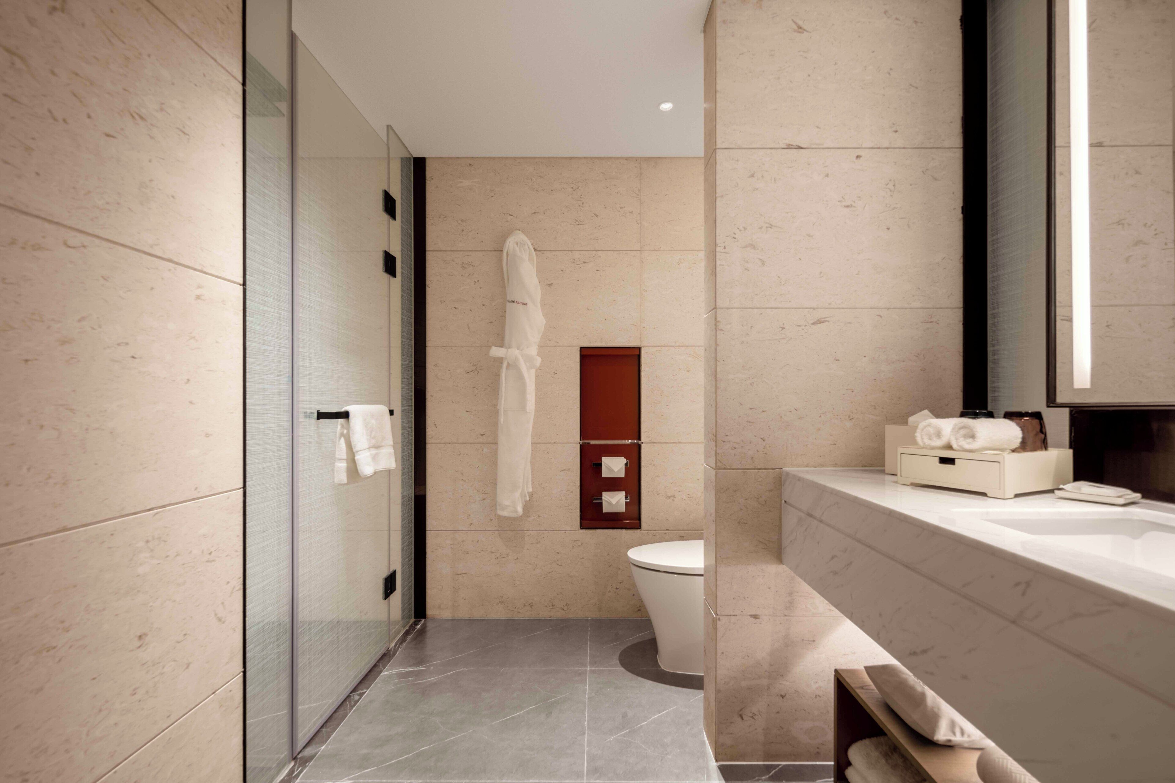 Un bagno moderno con box doccia in vetro, un water e un mobile lavabo con specchio.